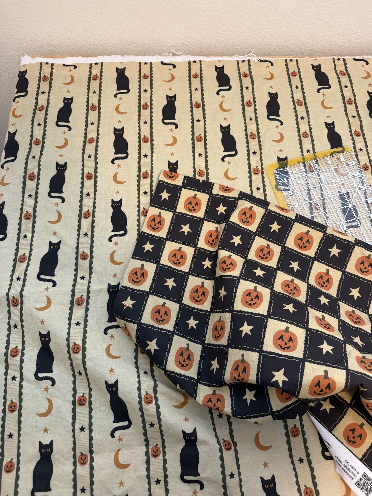 The cream cat print and the black and cream checkered jack o'lantern print from Spoonflower laid out together